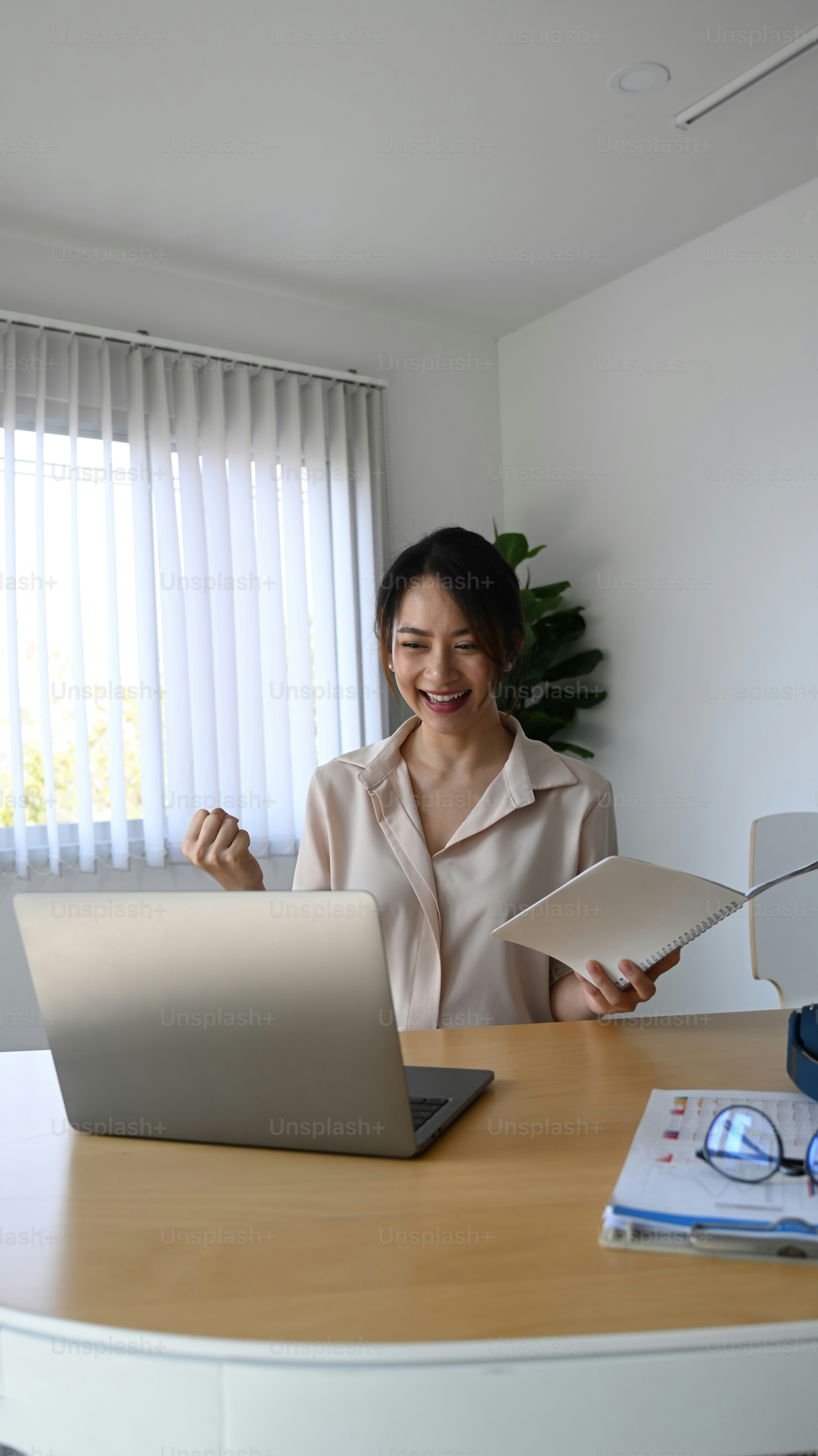 Happy businesswoman looking at laptop computer and celebrating her achievement office desk.